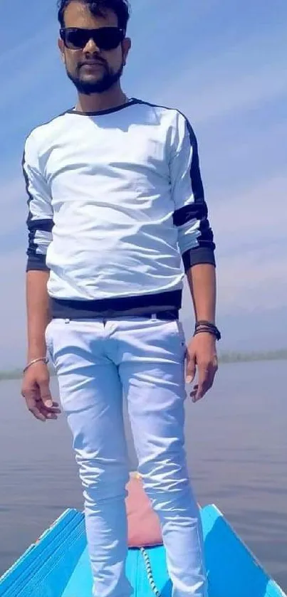 Man in stylish outfit posing on a boat with a blue sky background.