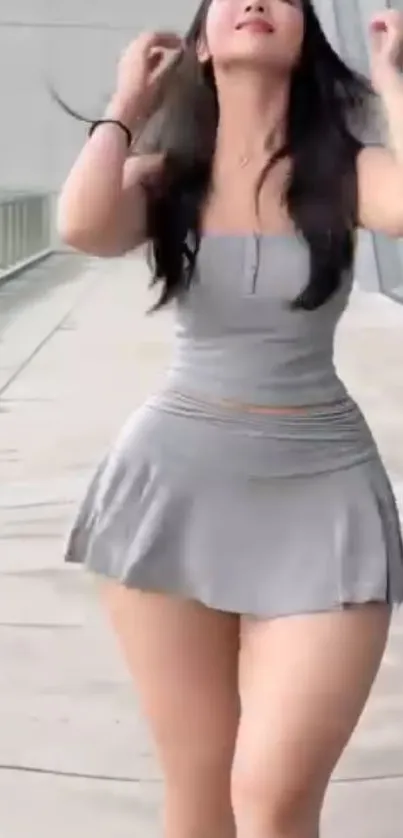 Fashionable woman in gray dress on a walkway.