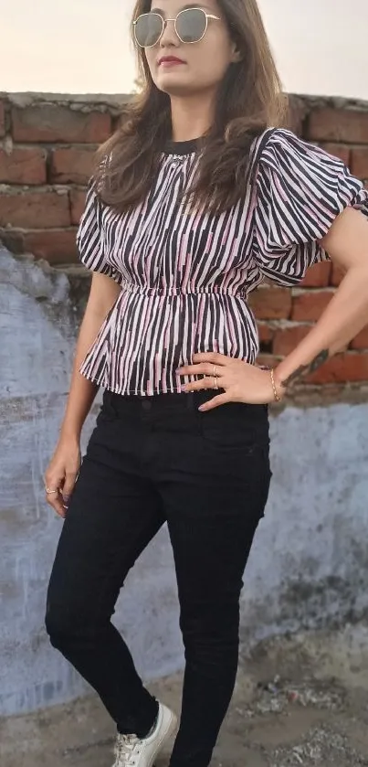Fashionable woman in striped top with brick background.