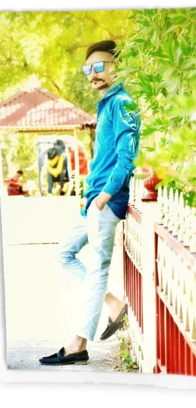 Stylish man in blue shirt by a colorful fence outdoors.