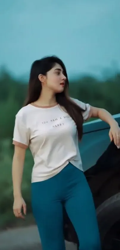 Fashionable woman in blue jeans by a car with a serene background.