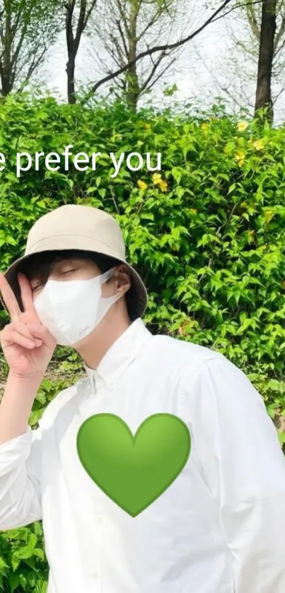 Man posing with peace sign in greenery and a heart emoji.