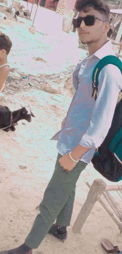 Man in sunglasses with village backdrop and goat.