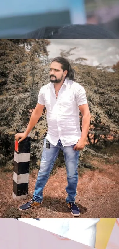 Man in white shirt and jeans standing outdoors with a scenic forest background.