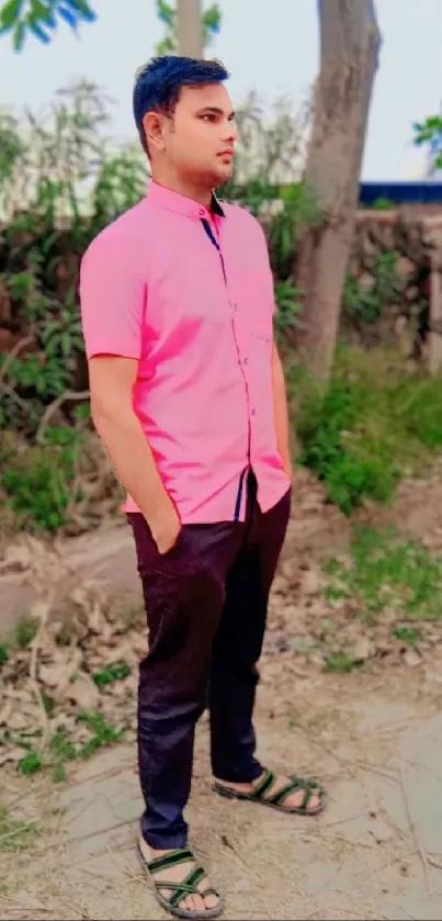 Young man in pink shirt posing outdoors.