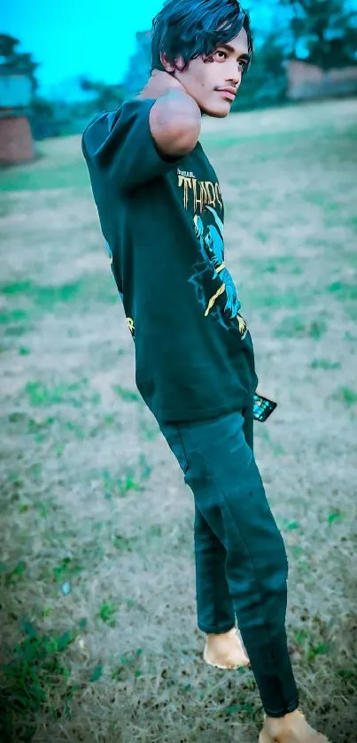 Man standing in green field wearing trendy clothes.