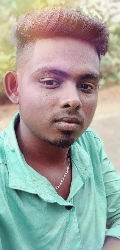 Young man in green shirt posing outdoors in natural light.