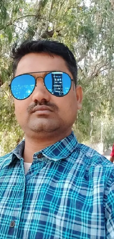 Man taking a selfie outdoors with reflective sunglasses.