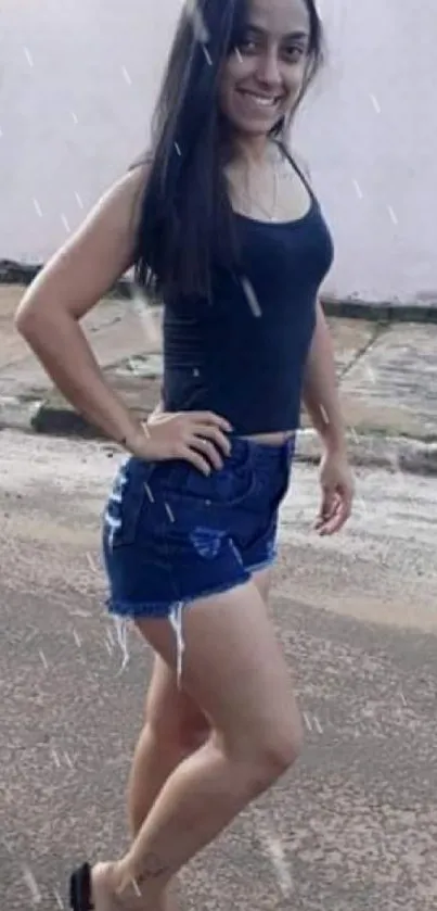 Woman in casual summer attire outdoors with denim shorts and black top.