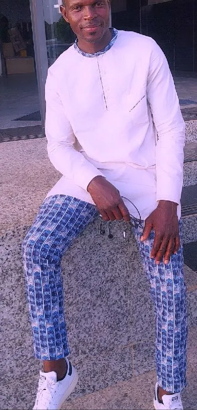 Man in stylish white and blue outfit on steps.