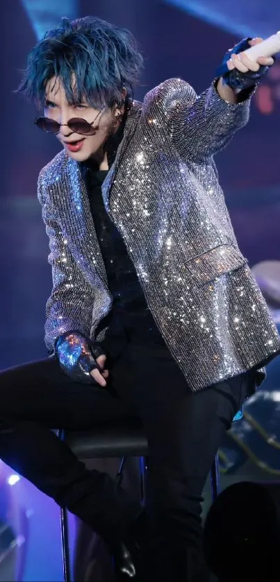 Performer in sparkly sequin jacket on stage with microphone.