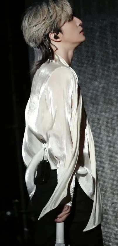 Performer in sleek outfit on stage at night.