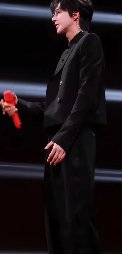 Performer in black with a red microphone, stylish wallpaper.