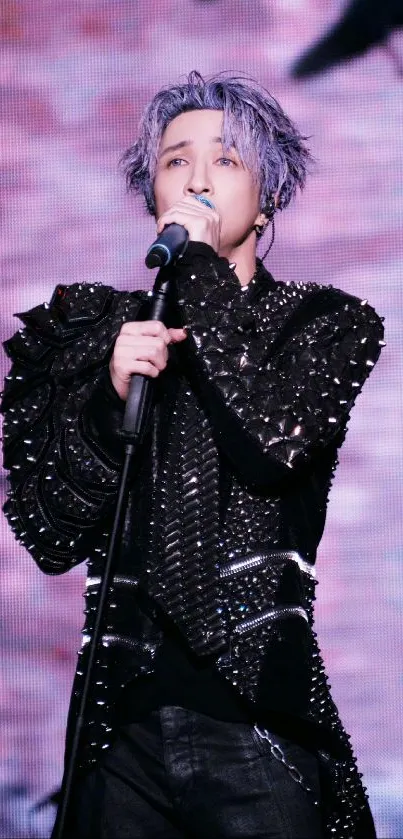 Stylish performer on stage in a studded outfit.