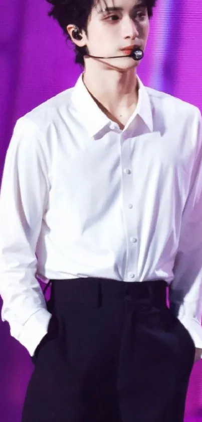 Stylish performer in a white shirt on stage with a purple background.