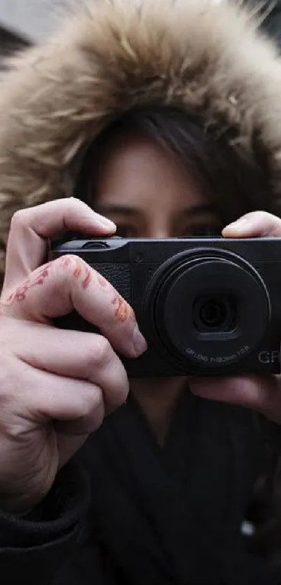 Person with henna holding a camera in a hoodie.