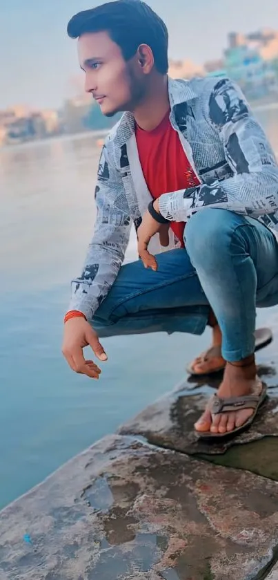 Young man posing by the lake in casual attire.