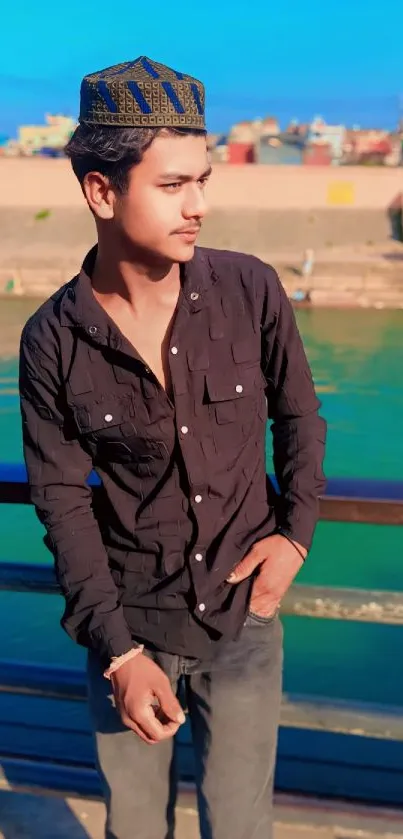 Young man in casual wear by riverside with urban background.