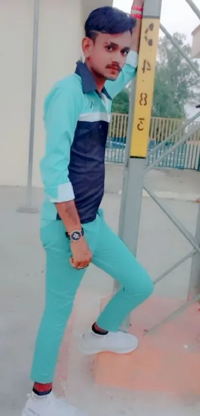 Man in cyan blue outfit poses stylishly outdoors.