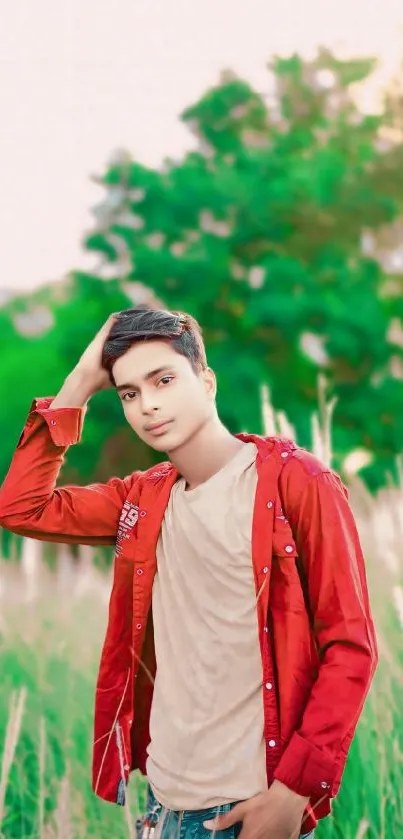 A young man poses in stylish attire with a lush green background.