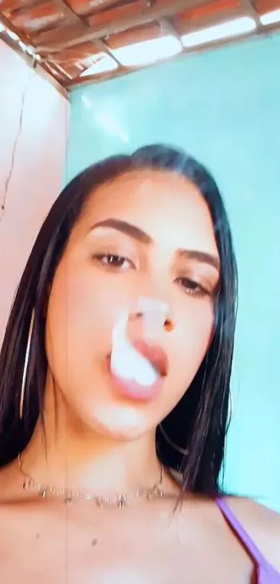 Young woman exhaling smoke with pastel wall backdrop.