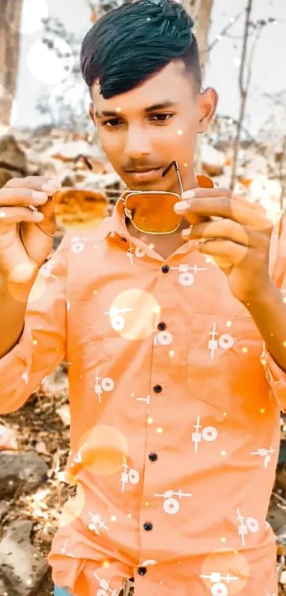 Young man in orange shirt with stylish sunglasses outdoors.