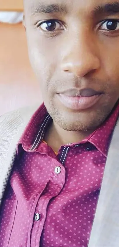 Close-up portrait of a man in a maroon polka-dot shirt and light brown blazer.