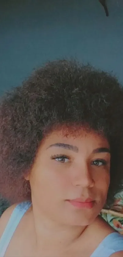 Stylish woman with curly hair in dark surroundings.