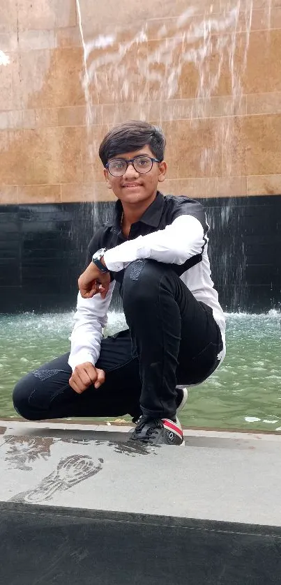 Young person poses stylishly by a waterfall.