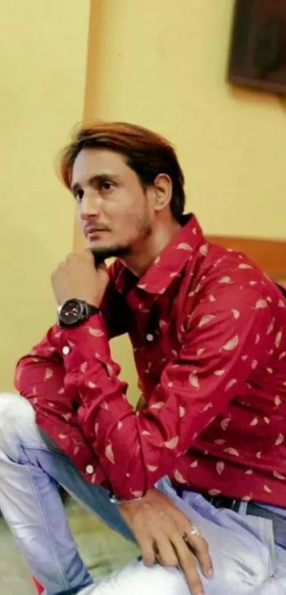 Man in red shirt posing thoughtfully indoors.