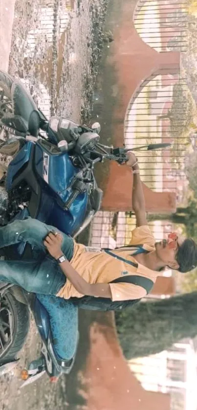 Young man posing stylishly with motorcycle against urban backdrop.