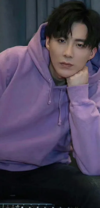 Person in a purple hoodie against a dark background.