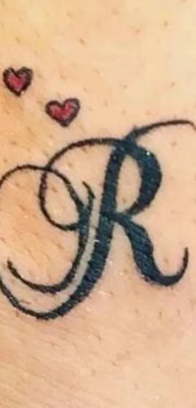 Elegant R letter tattoo with hearts on skin background.