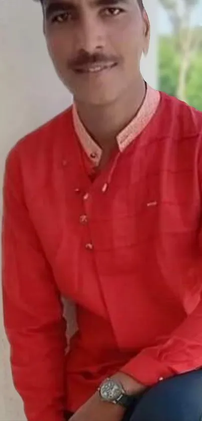 Man in a red shirt posing stylishly against a light background.