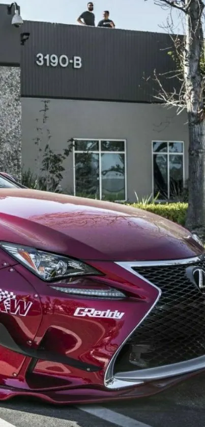 Red luxury car parked outside modern building.