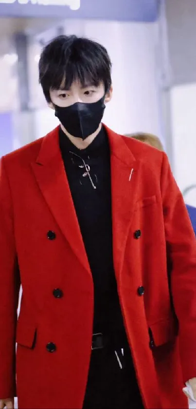 Person in a vibrant red coat and black mask, stylishly posed.