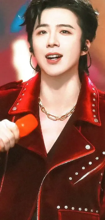 A person in a red jacket holding a microphone on stage.