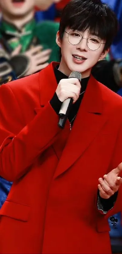 Performer in red coat holding microphone, smiling.