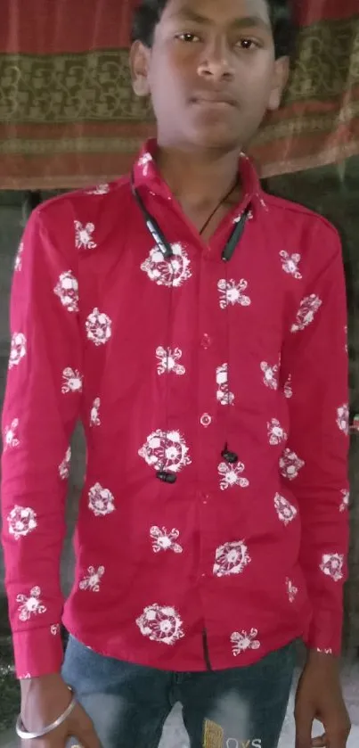 Young man wearing a red shirt stands confidently indoors.