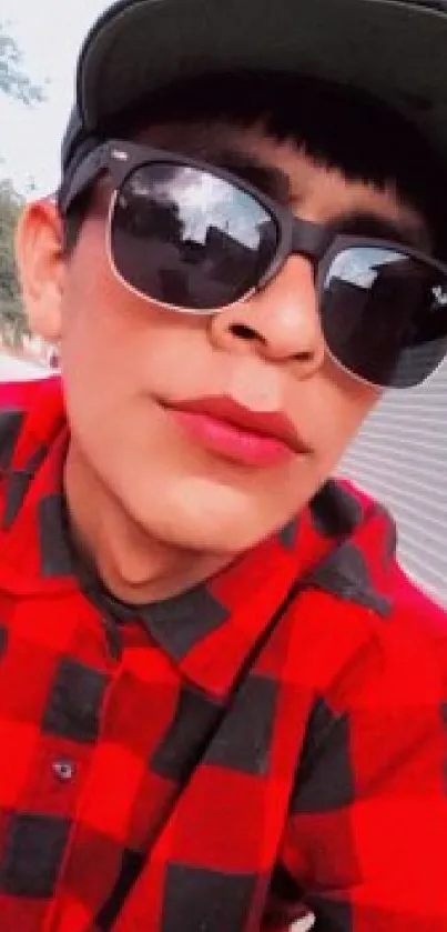 A person wearing a red plaid shirt and sunglasses, exuding a stylish and fashionable vibe.