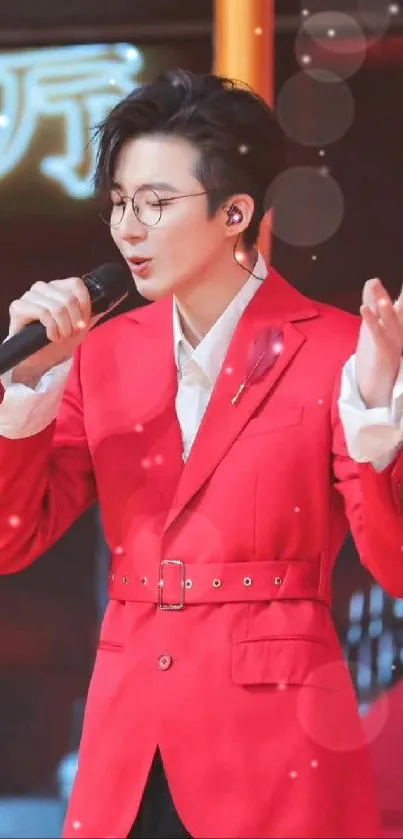 Performer in vibrant red suit on stage, singing into microphone.