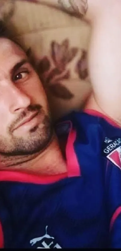 Relaxed man in vibrant sports jersey on sofa.