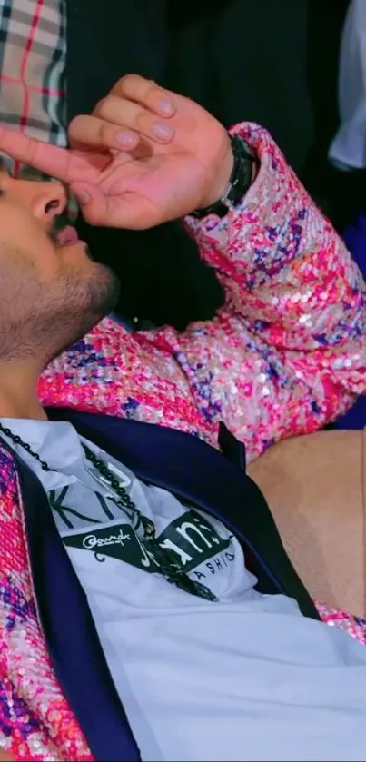 Man in a pink speckled jacket reclining on a sofa, exuding style and confidence.