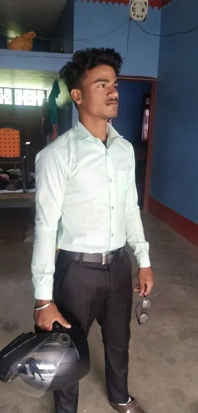 Young man stands in stylish blue room holding helmet.