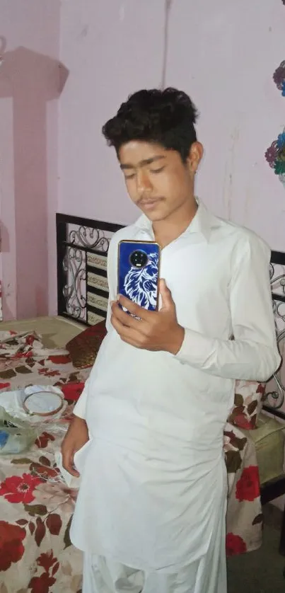 Man in stylish room with floral decor holding smartphone.