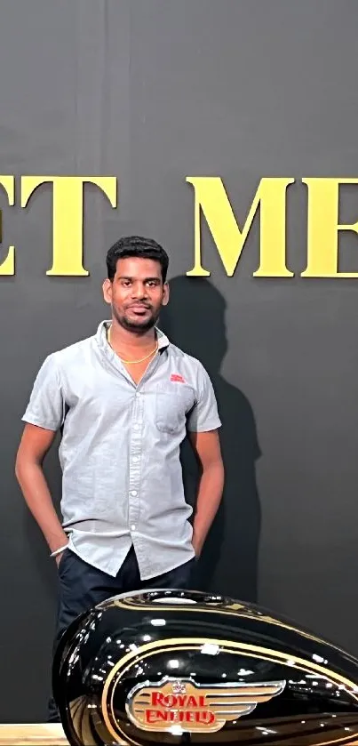 Man posing with Royal Enfield bike in stylish fashion.