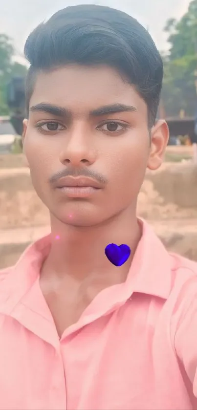 Young person in pink shirt with blue heart selfie wallpaper.