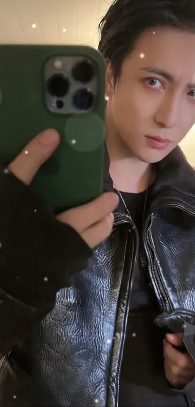 Stylish individual in dark leather jacket taking a selfie with phone.