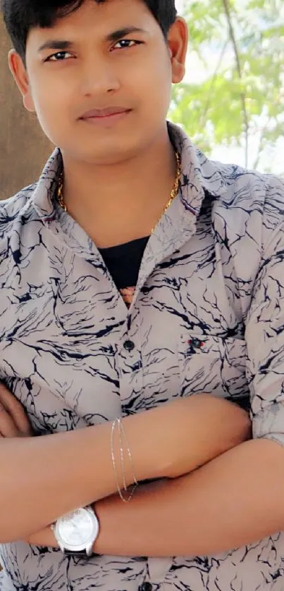 Stylish man in patterned shirt posing outdoors.