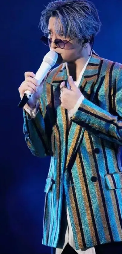 Singing performer in a bright, striped jacket on a blue-lit stage.